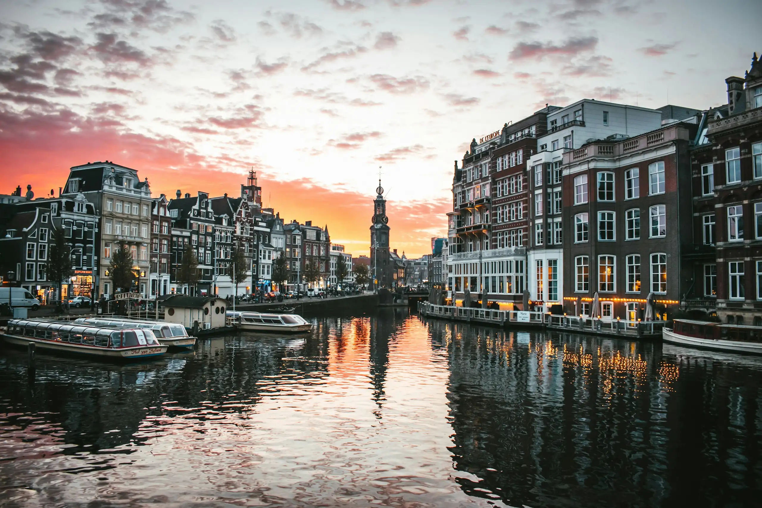 Un canal d’Amsterdam avec des bateaux et des maisons anciennes au coucher du soleil
