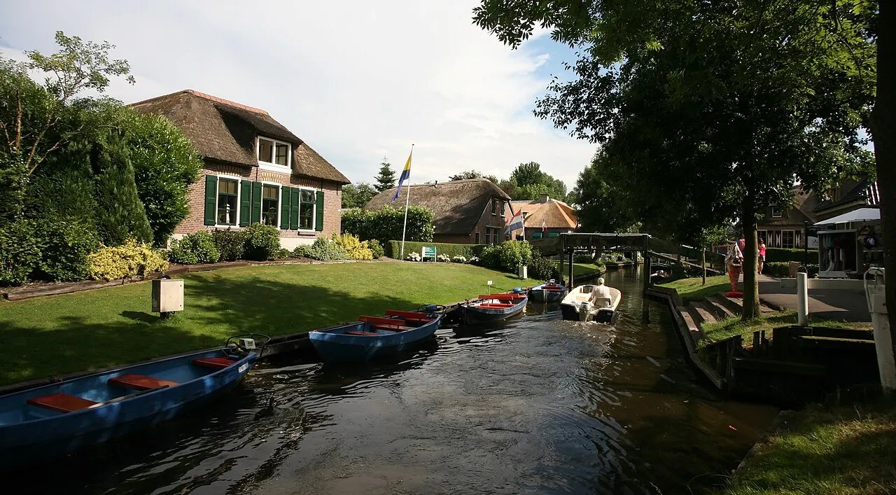 A Giethoorn canal with boats, a bridge and thatched houses