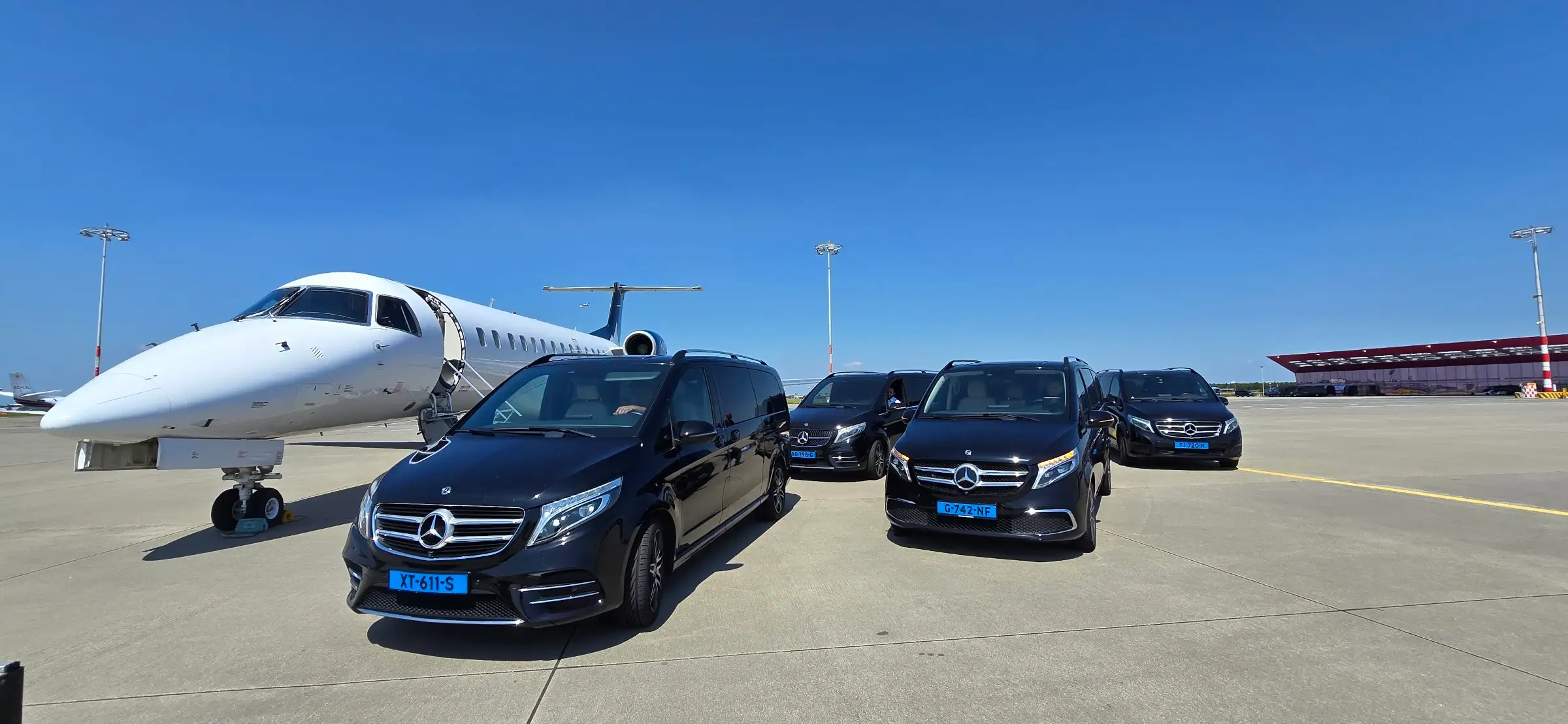 سيارات مرسيدس-بنز V‑Class سوداء بجانب طائرة رجال أعمال على ساحة مطار
